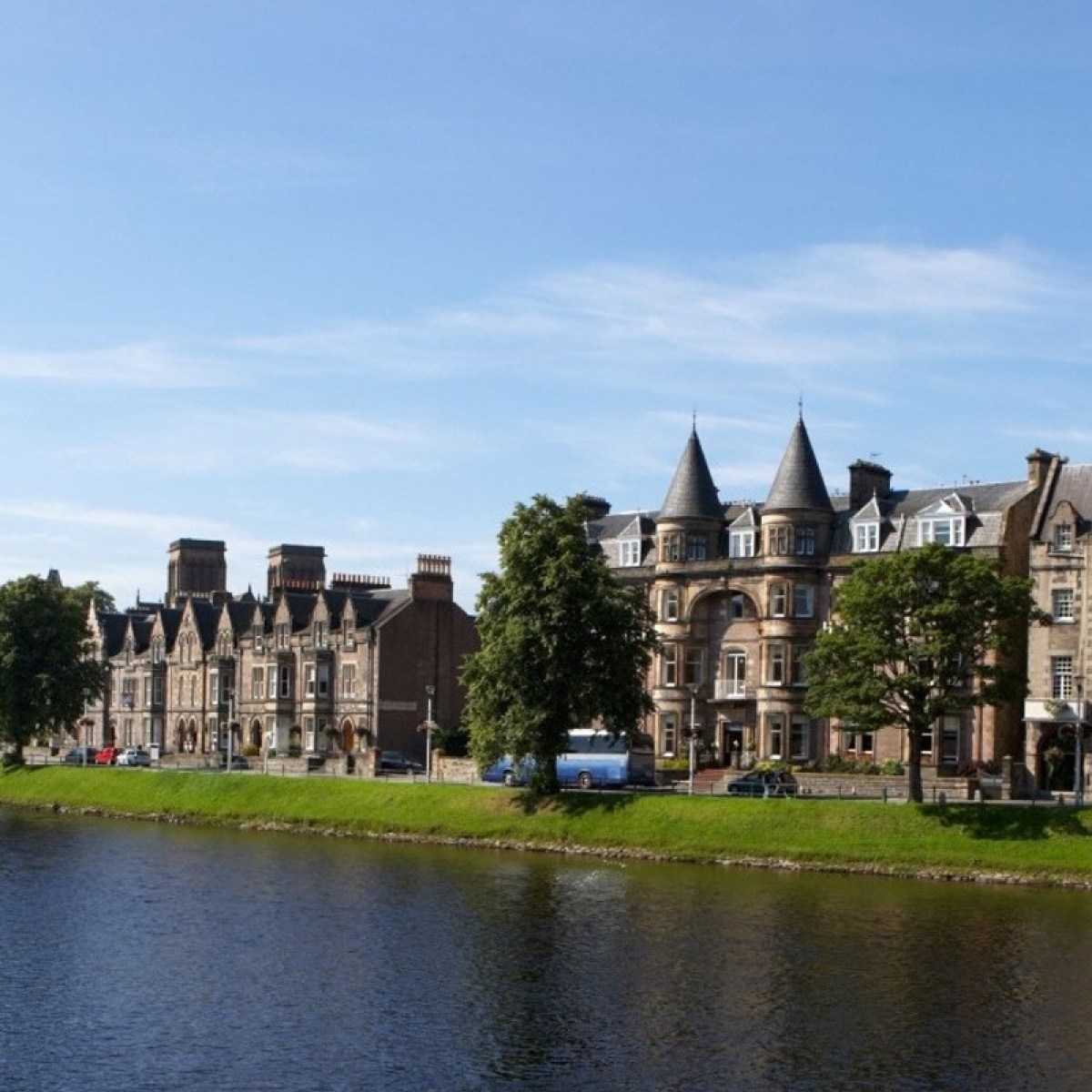 Riverside with historic stone buildings and blue sky background.