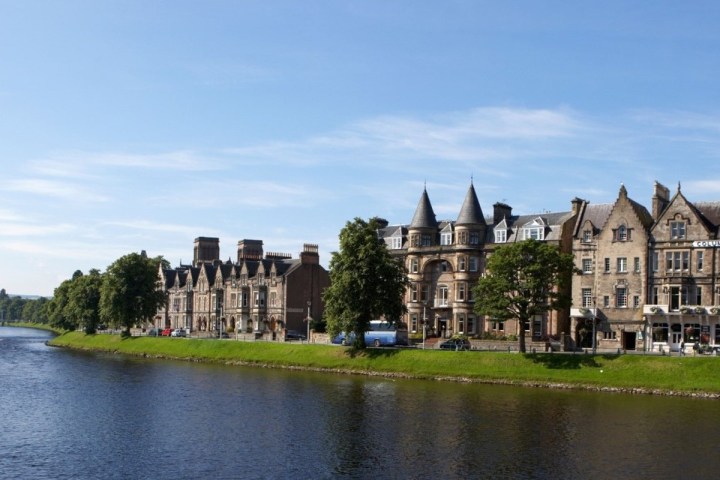 Riverside with historic stone buildings and blue sky background.